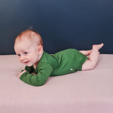 baby wearing merino long sleeve bodysuit green