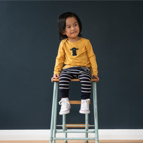 Child wearing merino baby long sleeve top canary yellow with print
