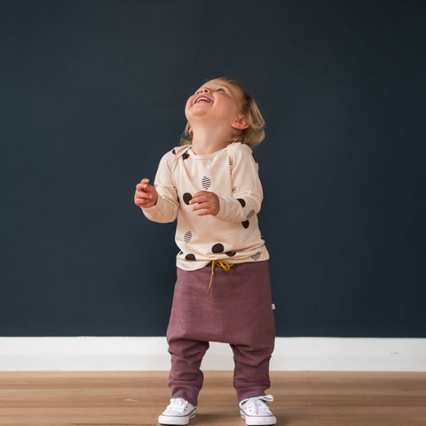 Child wearing merino baby long sleeve top dusky peach with orbit print