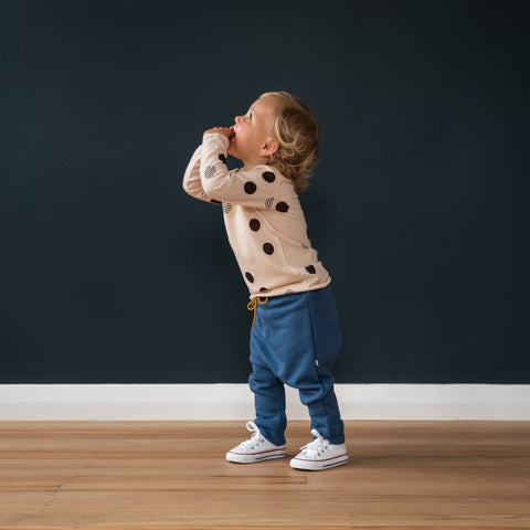Child wearing merino baby long sleeve top dusky peach with orbit print