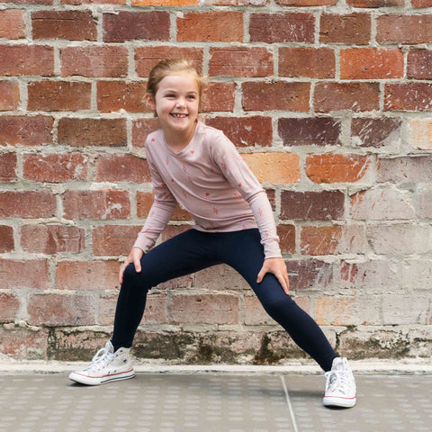 girl wearing merino long sleeve top in blush pink with print