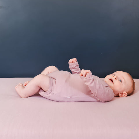 cute baby wearing merino long sleeve bodysuit in blush pink