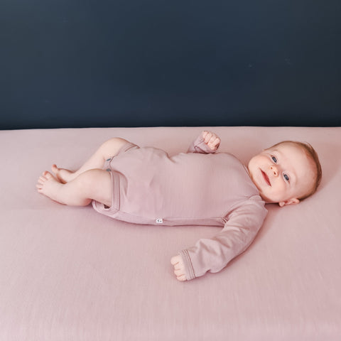 baby wearing merino long sleeve bodysuit in blush pink