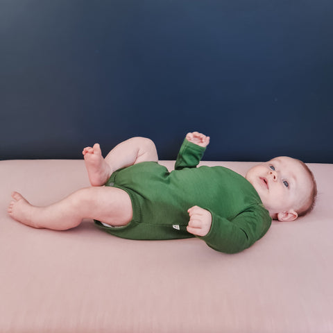 cute baby wearing merino long sleeve bodysuit green