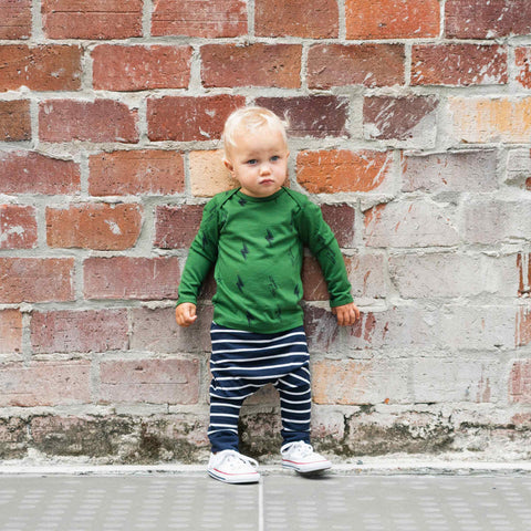 Child wearing slouch pants and merino baby long sleeve top moss green with print