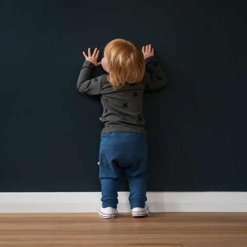 Child wearing trackies and merino baby long sleeve top dark grey with print