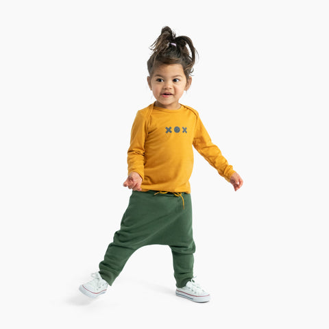 Child wearing merino baby long sleeve top nugget yellow with print