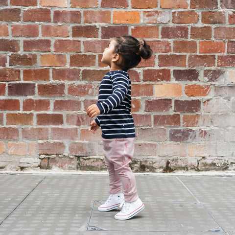 Girl wearing merino baby slouch pants blush pink with print