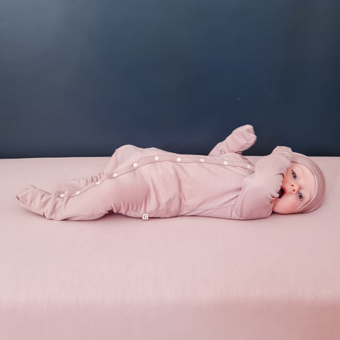 Baby wearing merino baby sleepsuit blush pink