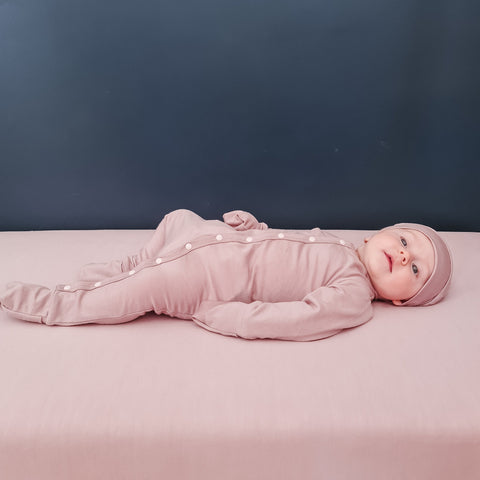 Baby girl wearing merino baby sleepsuit blush pink