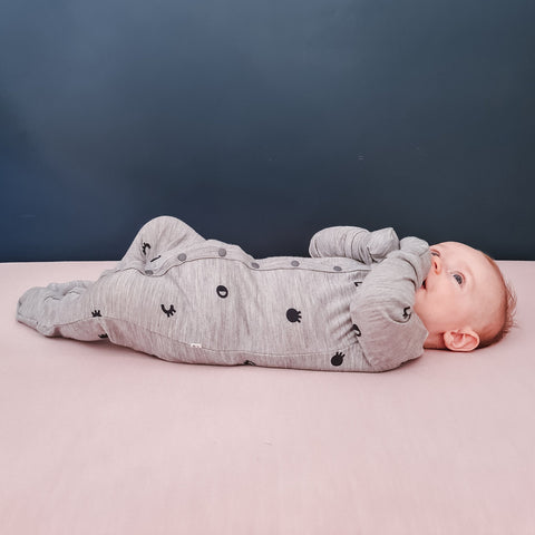 Baby boy wearing merino baby sleepsuit grey marl with print
